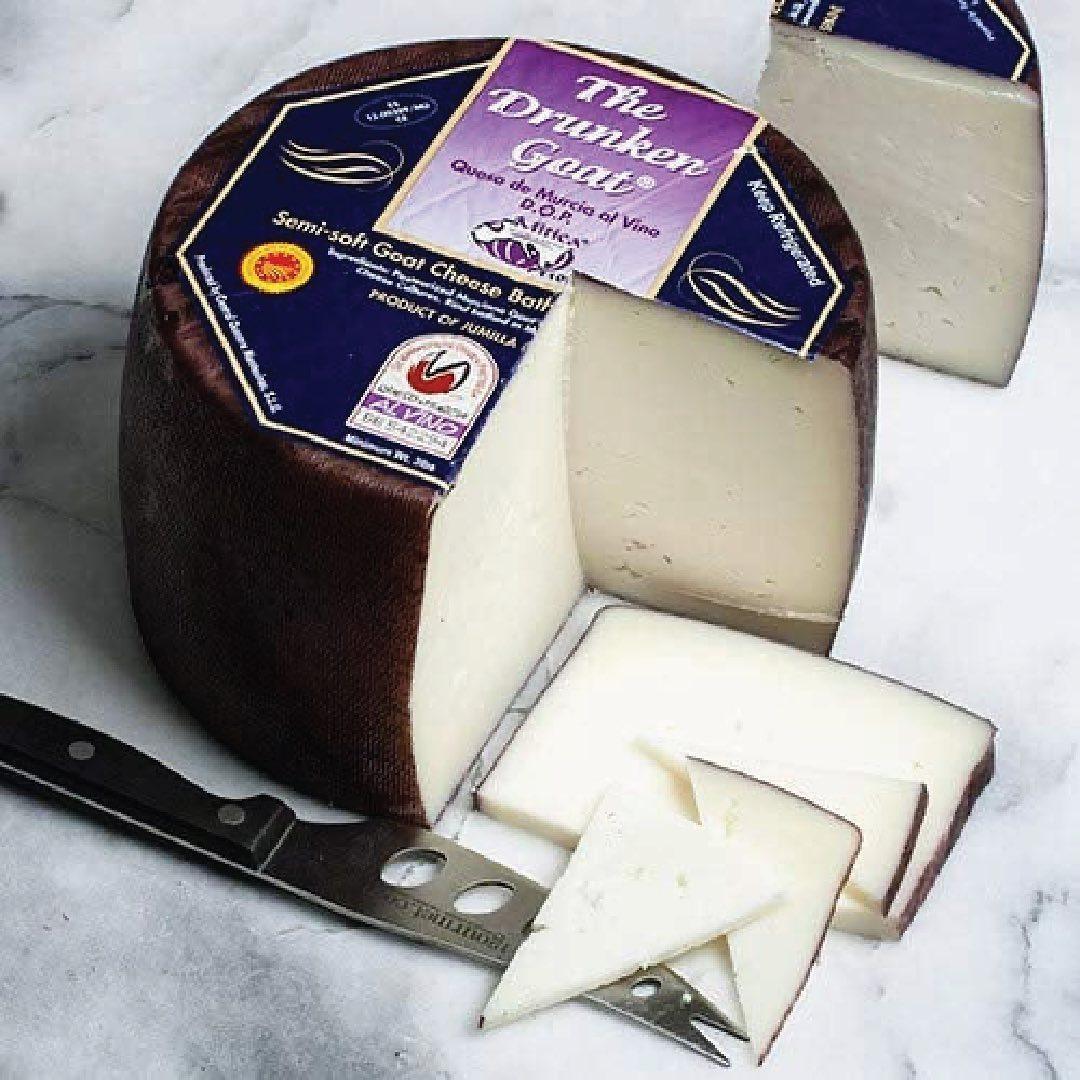 The Drunken Goat semi-soft goat cheese wheel with sliced pieces, artisanal Spanish D.O.P. cheese on marble