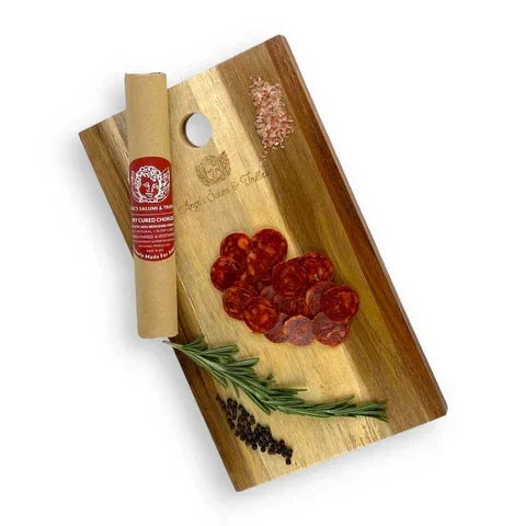 Artisan dry-cured chorizo slices on wooden board with rosemary, peppercorns, and Himalayan salt — premium, small-batch, clean-label charcuterie