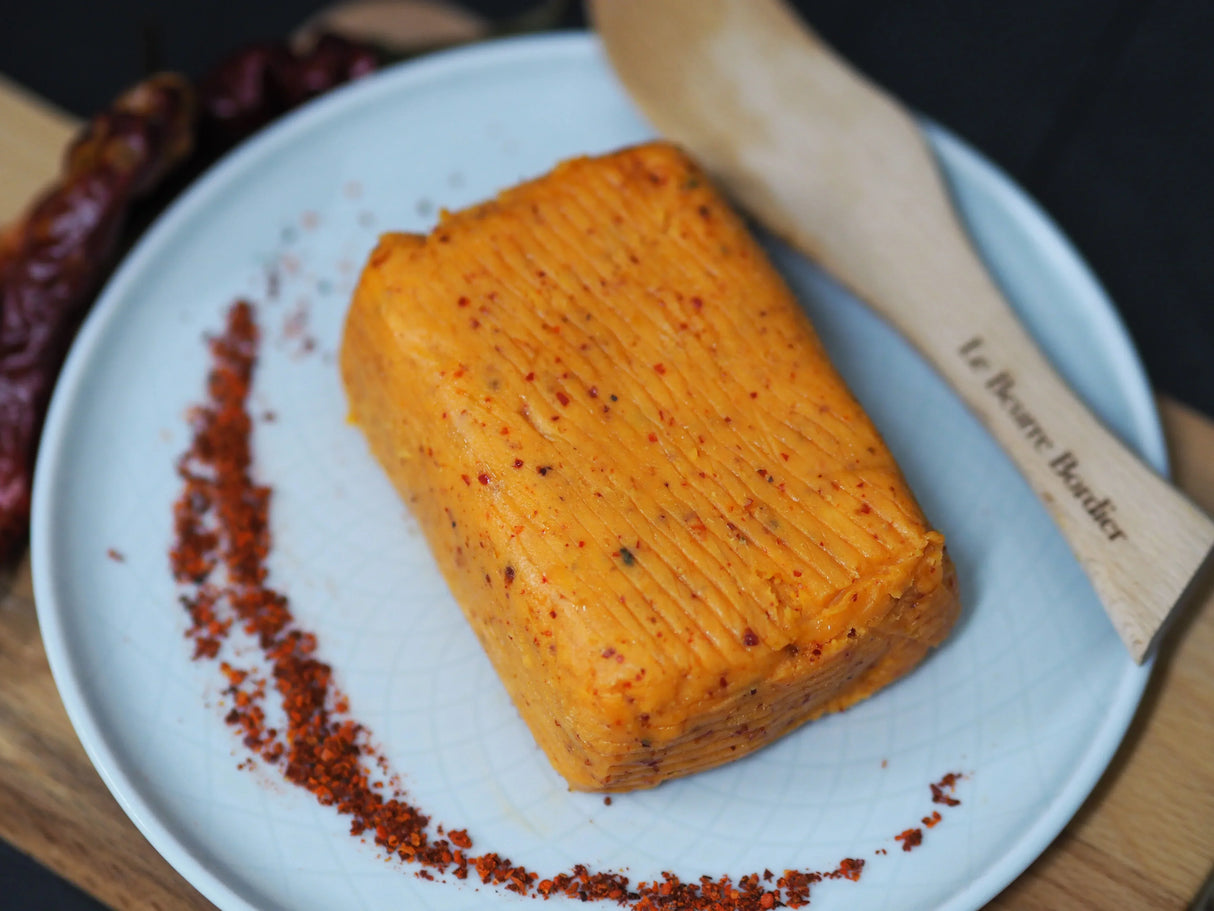 Spiced artisan butter with red pepper flakes, served on a plate with a wooden spreader