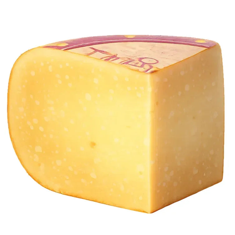 Artisan French cheese wheel with creamy yellow interior, small holes, and purple rind label