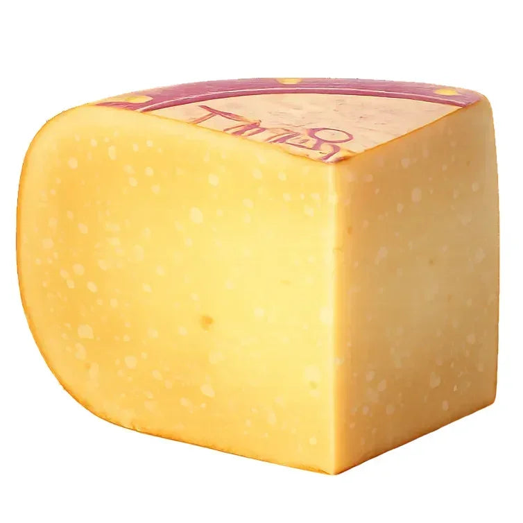 Artisan French cheese wheel with creamy yellow interior, small holes, and purple rind label