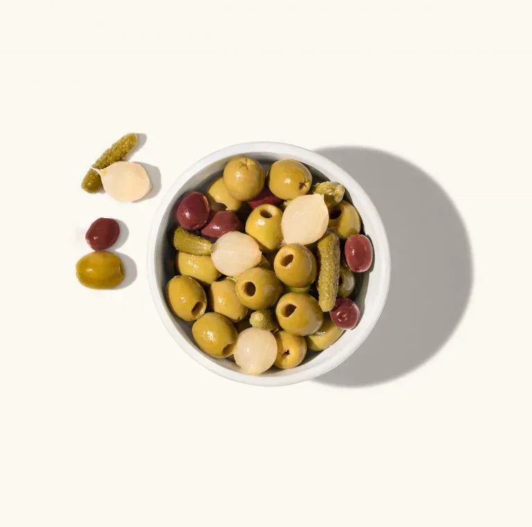 Assorted olives and pickles in a white bowl, artisan-made, gluten-free, premium quality