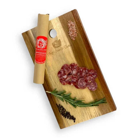 Wooden board with sliced cured French sausage, rosemary, black pepper, and sea salt.