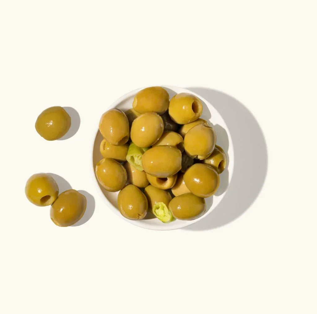 Green olives with jalapeño slices in a white bowl, artisan-made, clean-label, premium quality