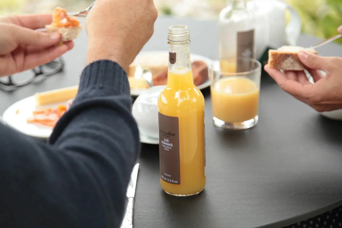 French pineapple juice bottle with bread and cheese on a table