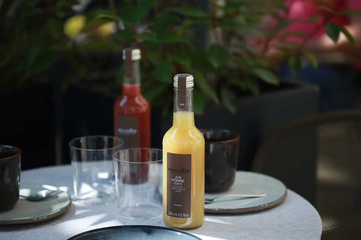 Cloudy Cox's Apple Juice from France, artisan-made, premium quality, served on a table with glasses and plates.