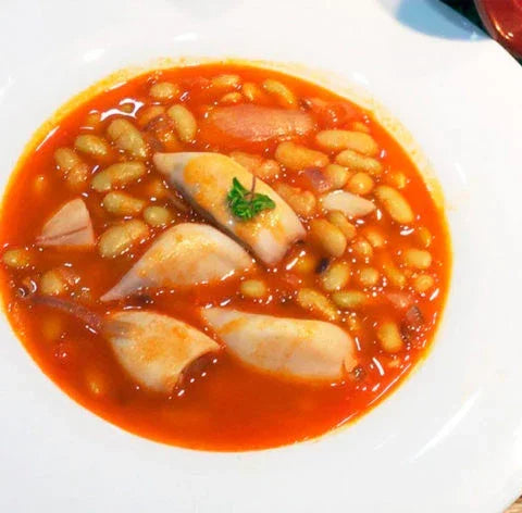 Squid and white beans in tomato sauce, garnished with herbs, artisan-made Spanish dish