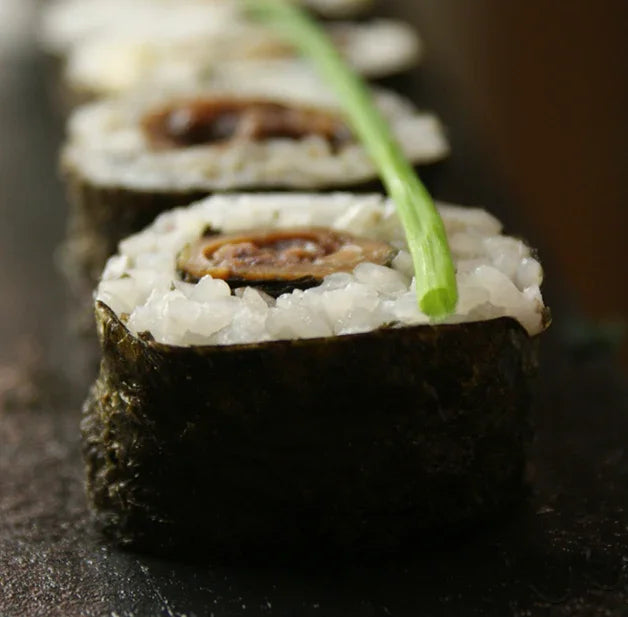 Gourmet chipirones maki sushi roll with seaweed, rice, and garnish on black plate