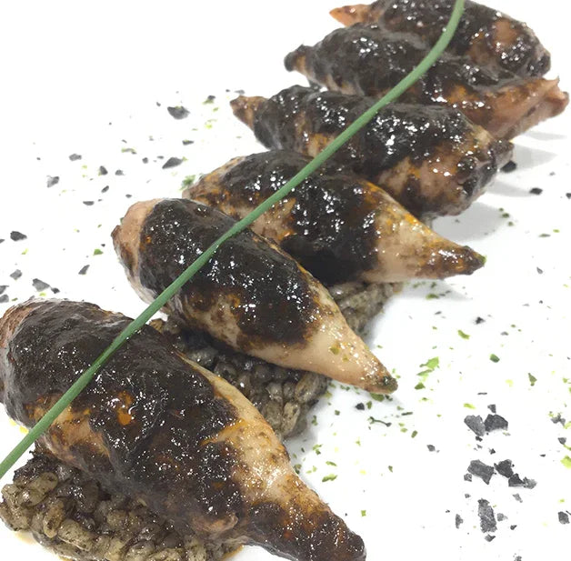 Gourmet chipirones stuffed squid with squid ink rice on white plate, French Pantry specialty
