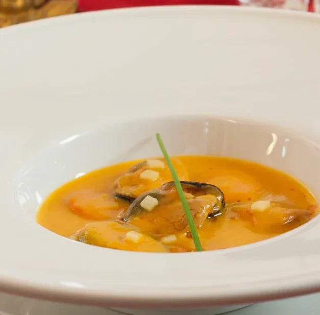 Creamy mussel soup with herbs in a white bowl, artisan Spanish cuisine
