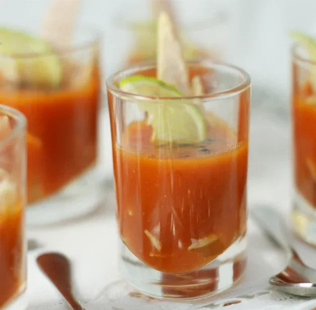 Tomato soup shots garnished with lime slices and croutons, artisanal and gluten-free