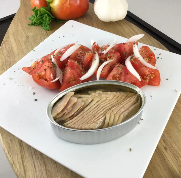 Premium French canned tuna with fresh tomato and onion salad on white plate