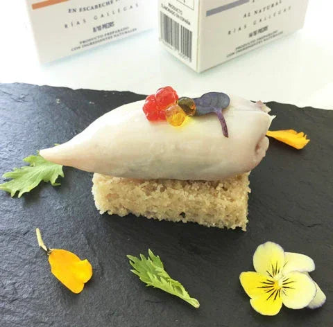 Baby squid on toasted bread with roe pearls and edible flowers on slate, Spanish seafood appetizer