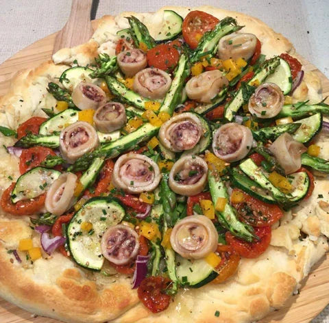Artisan pizza topped with zucchini, asparagus, cherry tomatoes, and mushrooms, fresh and gourmet.