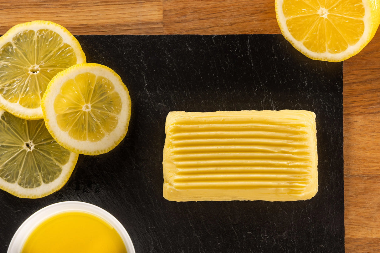 Artisan French butter with lemon slices on slate, showcasing premium, all-natural, grass-fed quality