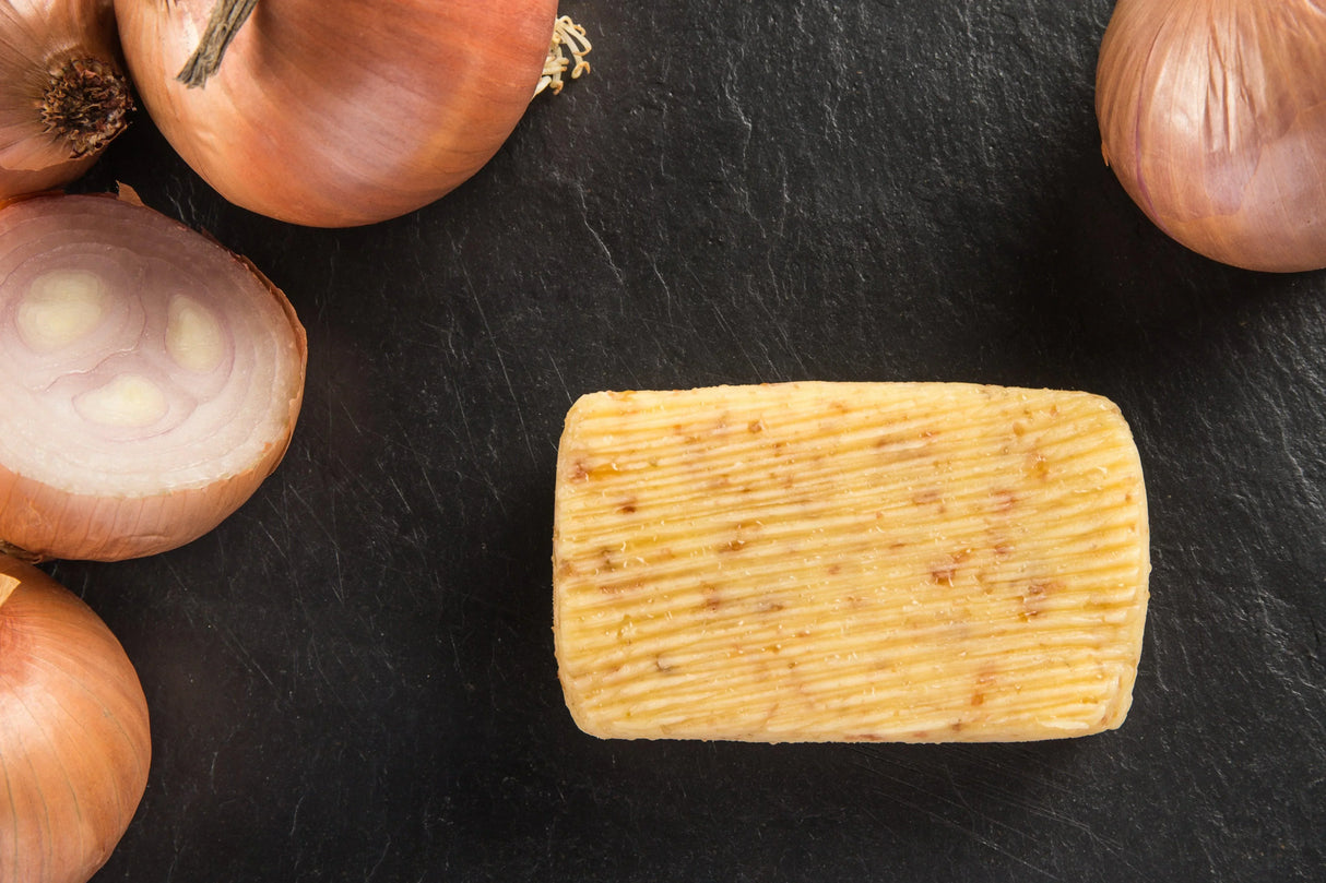 Bordier Roscoff onion butter block on slate surrounded by fresh onions, hand-churned French butter