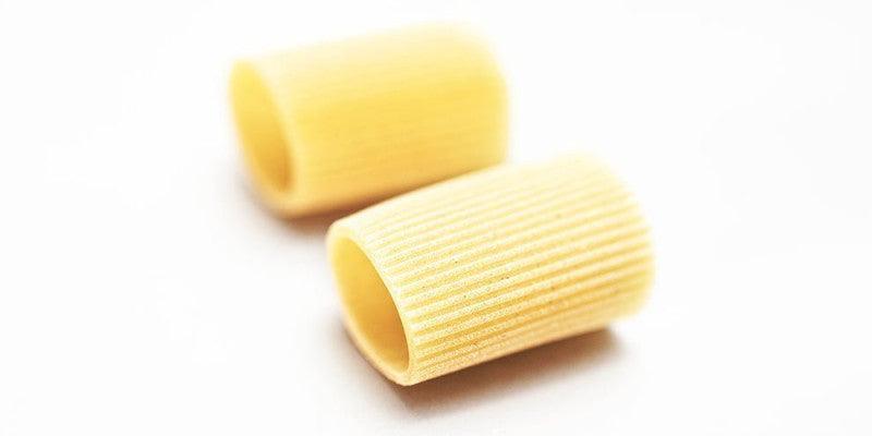 Two pieces of artisanal Italian pasta with ridged texture, perfect for premium sauces