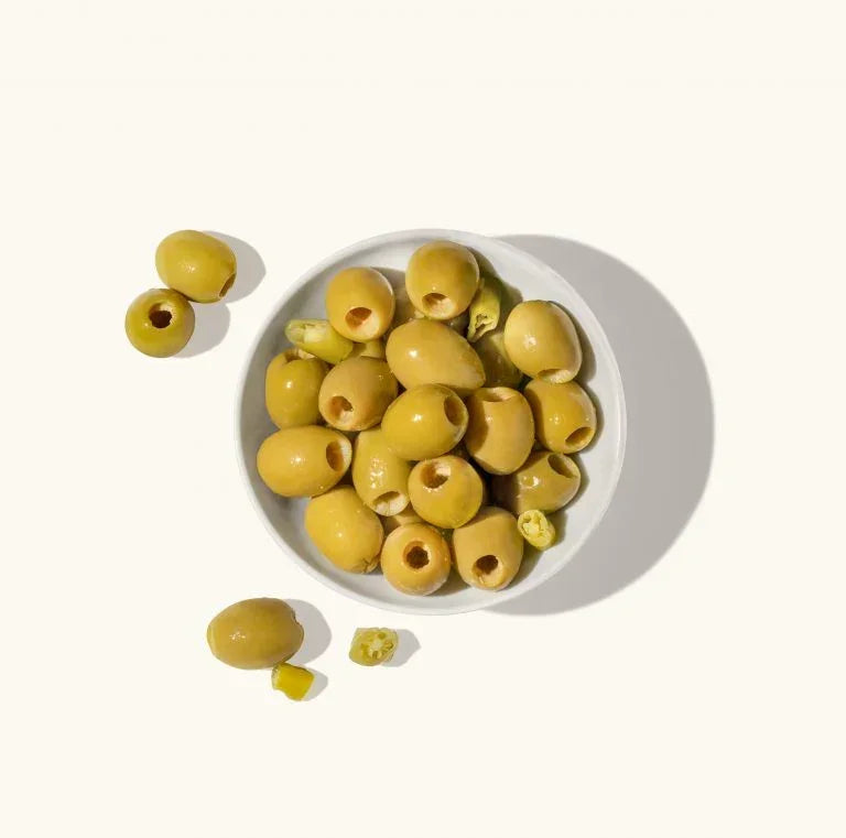 Pitted green olives with jalapeño slices in white bowl, artisanal snack, gluten-free, keto-friendly