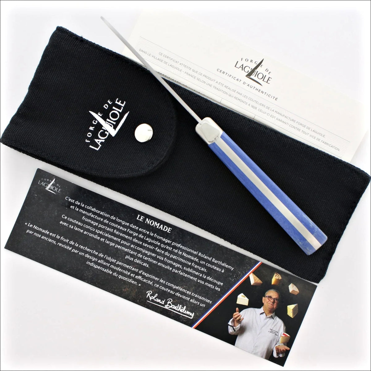 Forge de Laguiole Le Nomade cheese knife with blue handle, black pouch, and authenticity certificate.