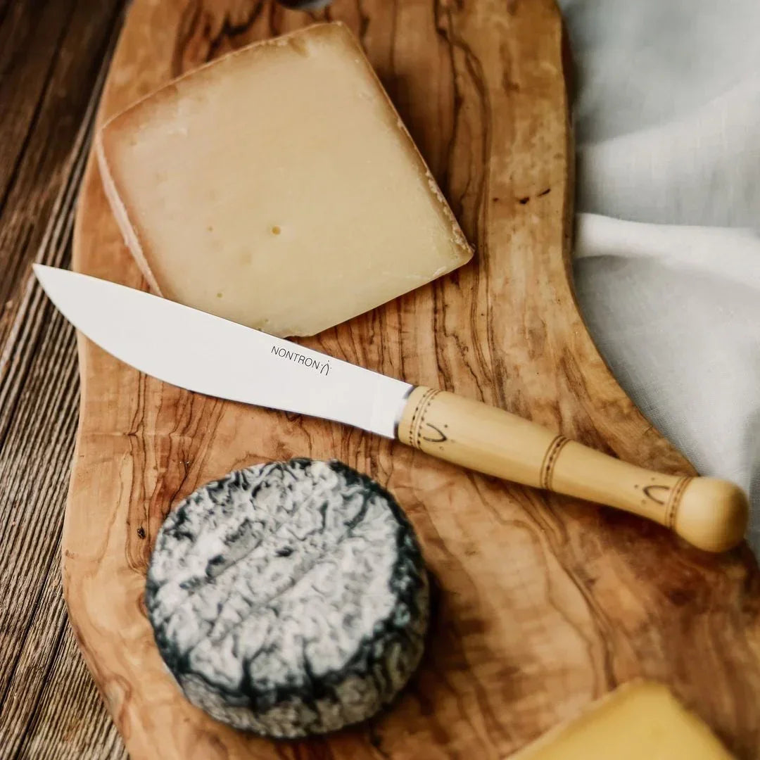 Artisan French cheeses on wooden board with cheese knife, premium all-natural gourmet selection
