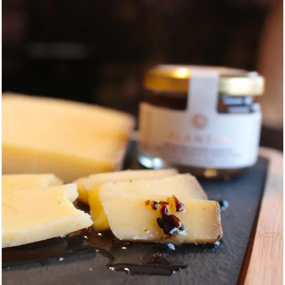 Artisan French cheese slices with honey drizzle, paired with premium jam on slate board
