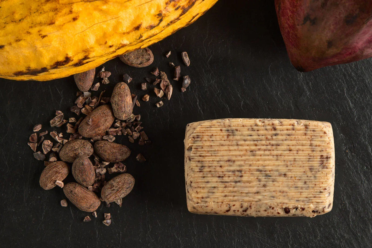 Artisanal butter with cocoa nibs, cacao pods, and beans on dark slate