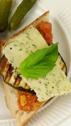 Grilled eggplant sandwich with herb cheese, basil, and tomato, served with pickles