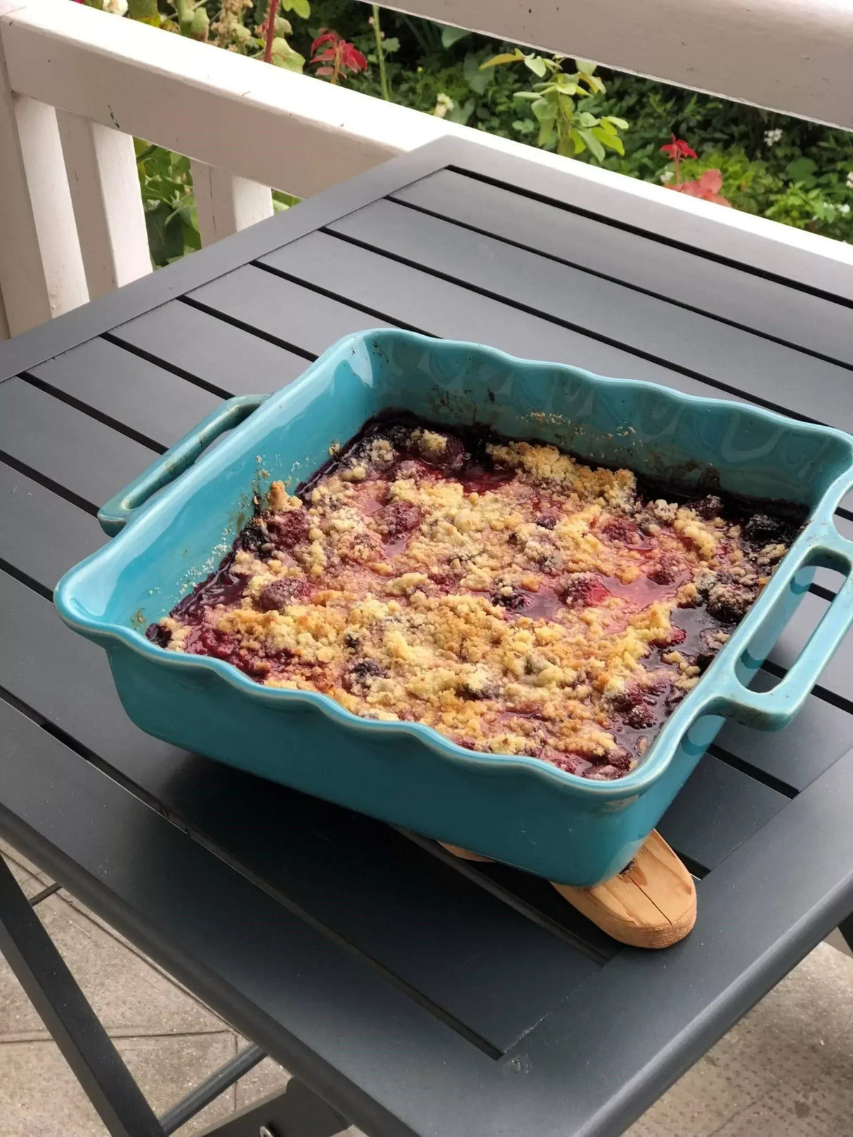 Berry crumble dessert in turquoise baking dish on outdoor table