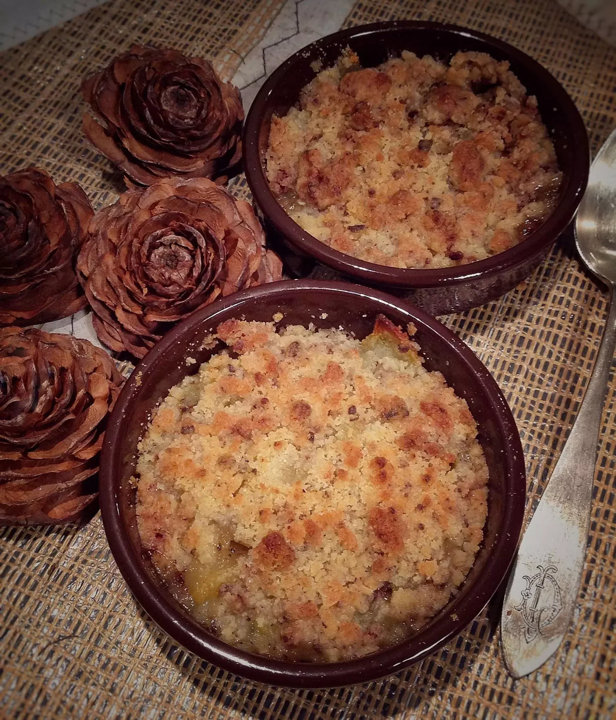 Golden-brown French crumble dessert in rustic bowls with pinecones, artisan-made and gluten-free