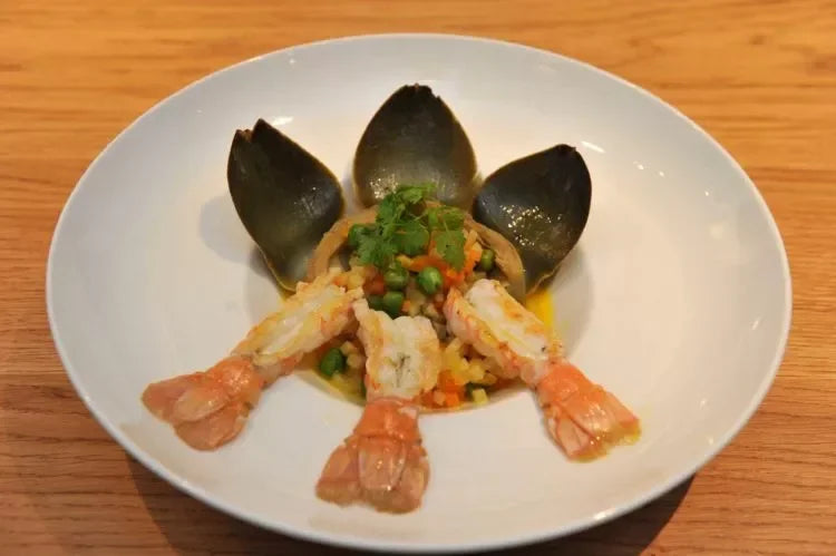 Elegant seafood dish with prawns, mussels, and colorful vegetables on a white plate