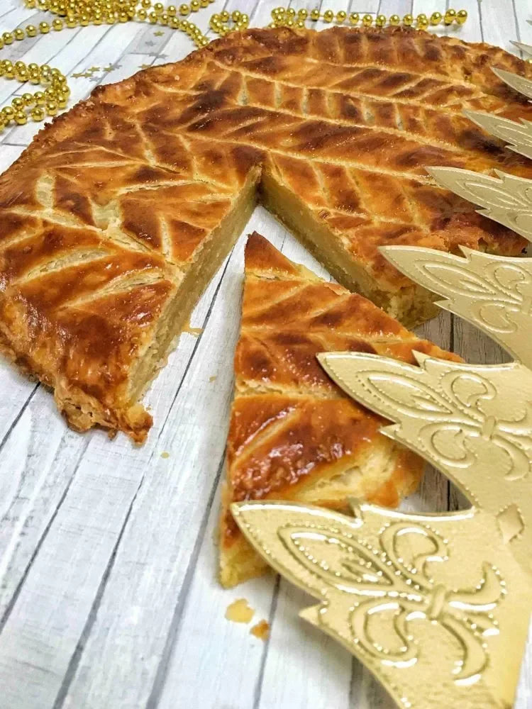 Golden-brown French galette with flaky crust, sliced and served with festive gold decorations.