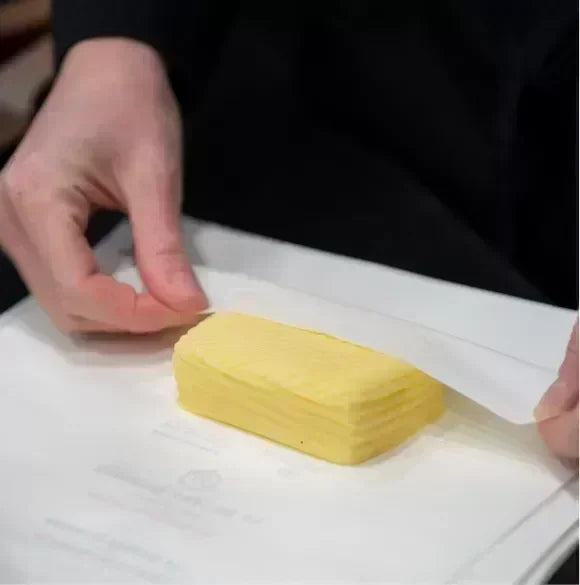 Premium French butter block unwrapped, showcasing rich yellow layers, artisan-made, all-natural