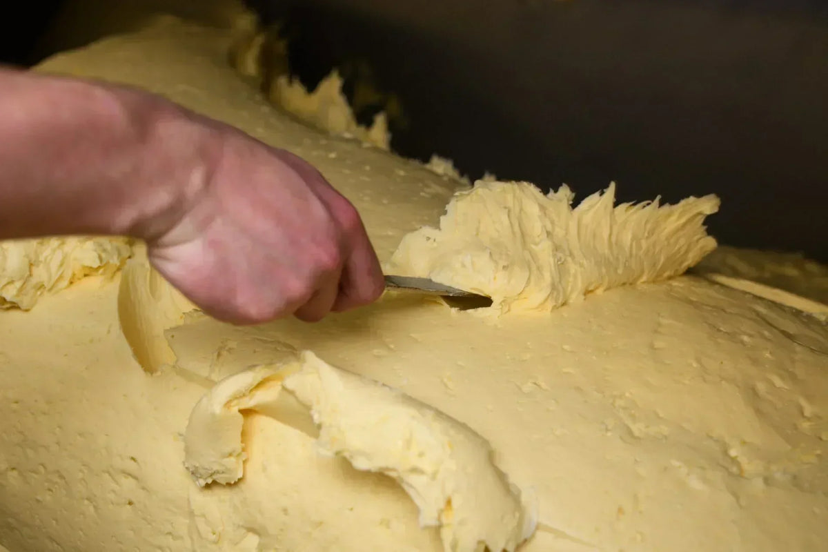 Artisan hand crafting premium French butter with a spatula, showcasing creamy texture and small-batch quality.