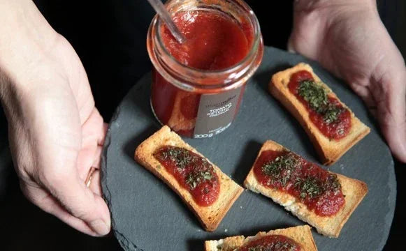 Artisan French tomato jam served on toasted bread with herbs, perfect for gourmet appetizers.