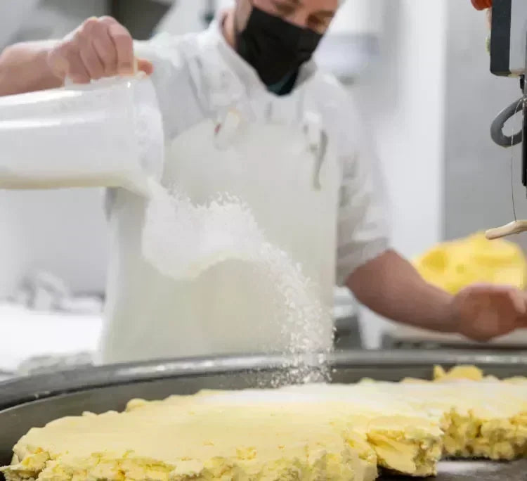 Artisan pouring milk over fresh French butter in a clean kitchen setting