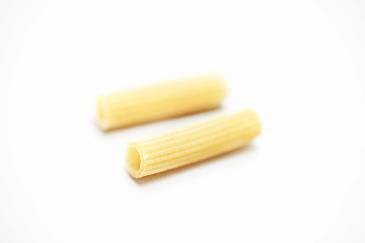 Two pieces of rigatoni pasta on a white background