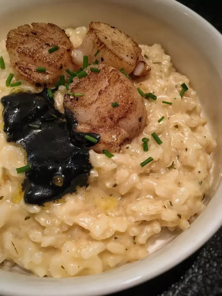 Creamy risotto with seared scallops, caviar, and chives, gourmet French-inspired dish