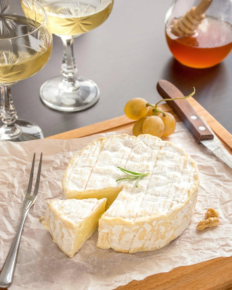French cheese wheel with rosemary, grapes, honey, and white wine for pairing