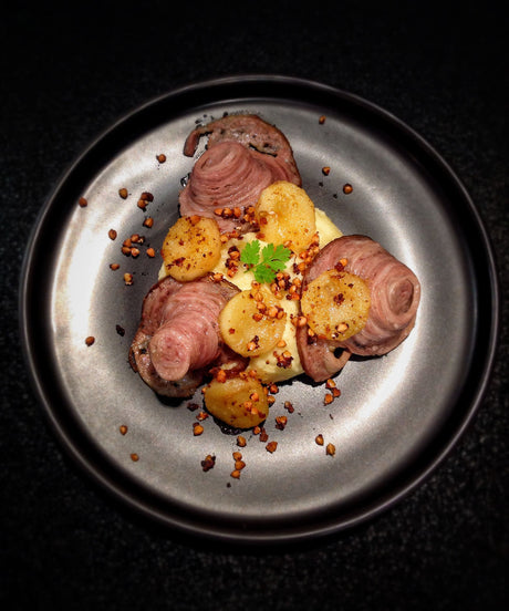 Plated andouille sausage slices with roasted apple wedges and onion butter mashed potatoes topped with toasted buckwheat