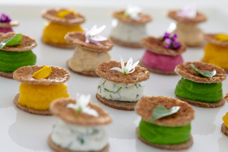 Small buckwheat crepe disks layered with herbed goat cheese and beet puree, decorated with herbs and flowers