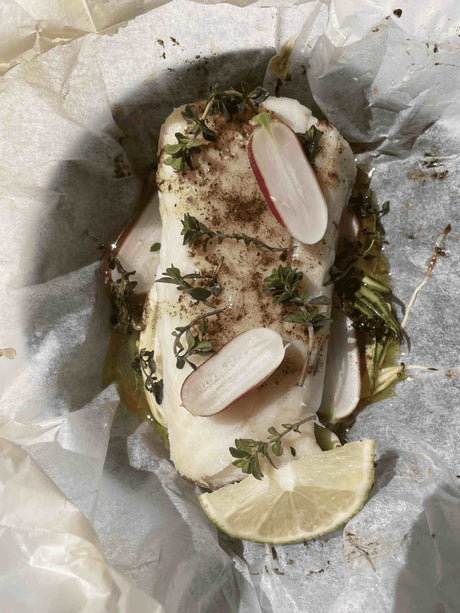 Cod fillet baked in a paper parcel with zucchini ribbons, sliced radishes, thyme and vanilla butter