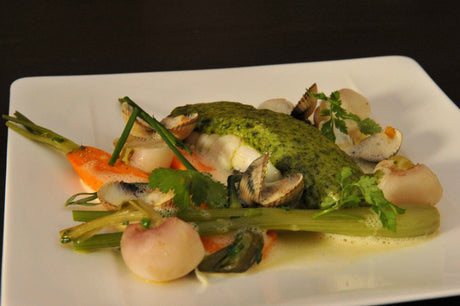 Cod baked under a herb butter crust with cockles and baby spring vegetables on a serving platter
