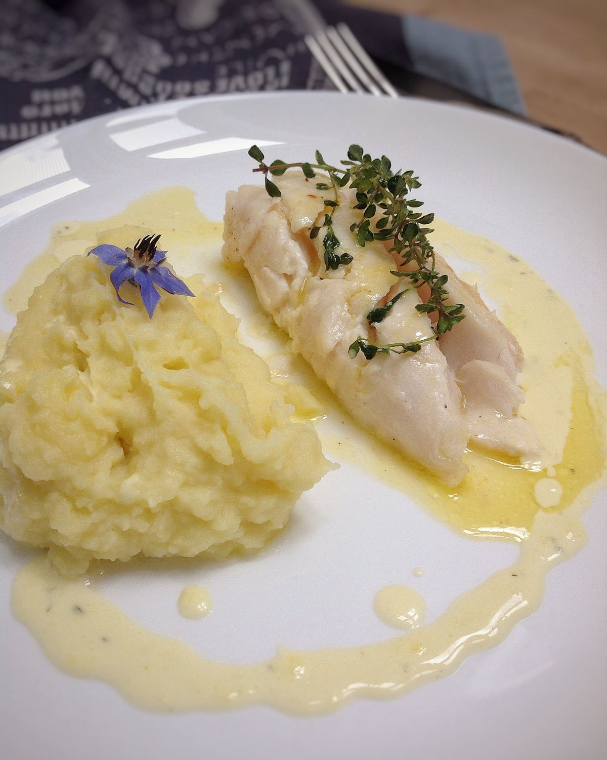 Roast cod fillet on mashed potatoes with an emulsified butter sauce and lemon thyme