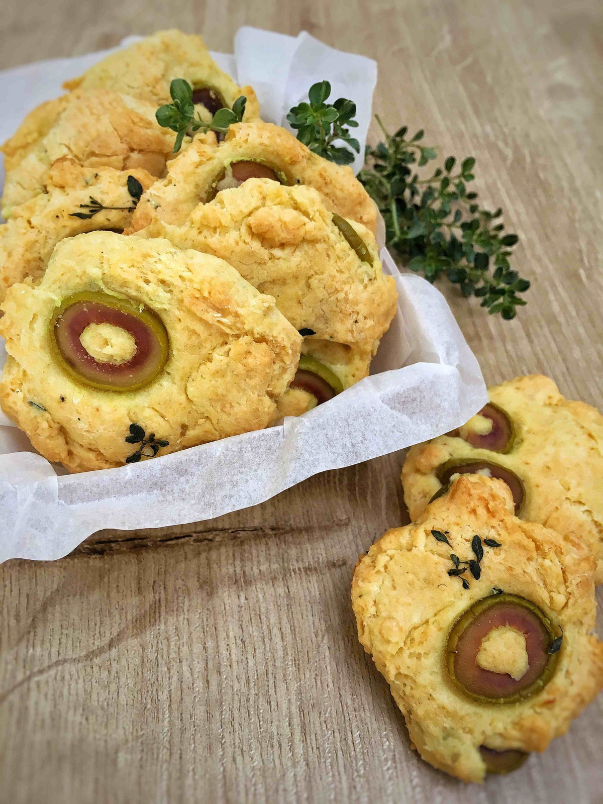 Savory olive and parmesan cookies scattered with thyme leaves