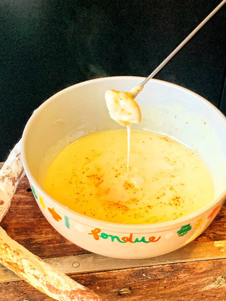 A caquelon of Savoyard cheese fondue with cubes of stale white bread on forks
