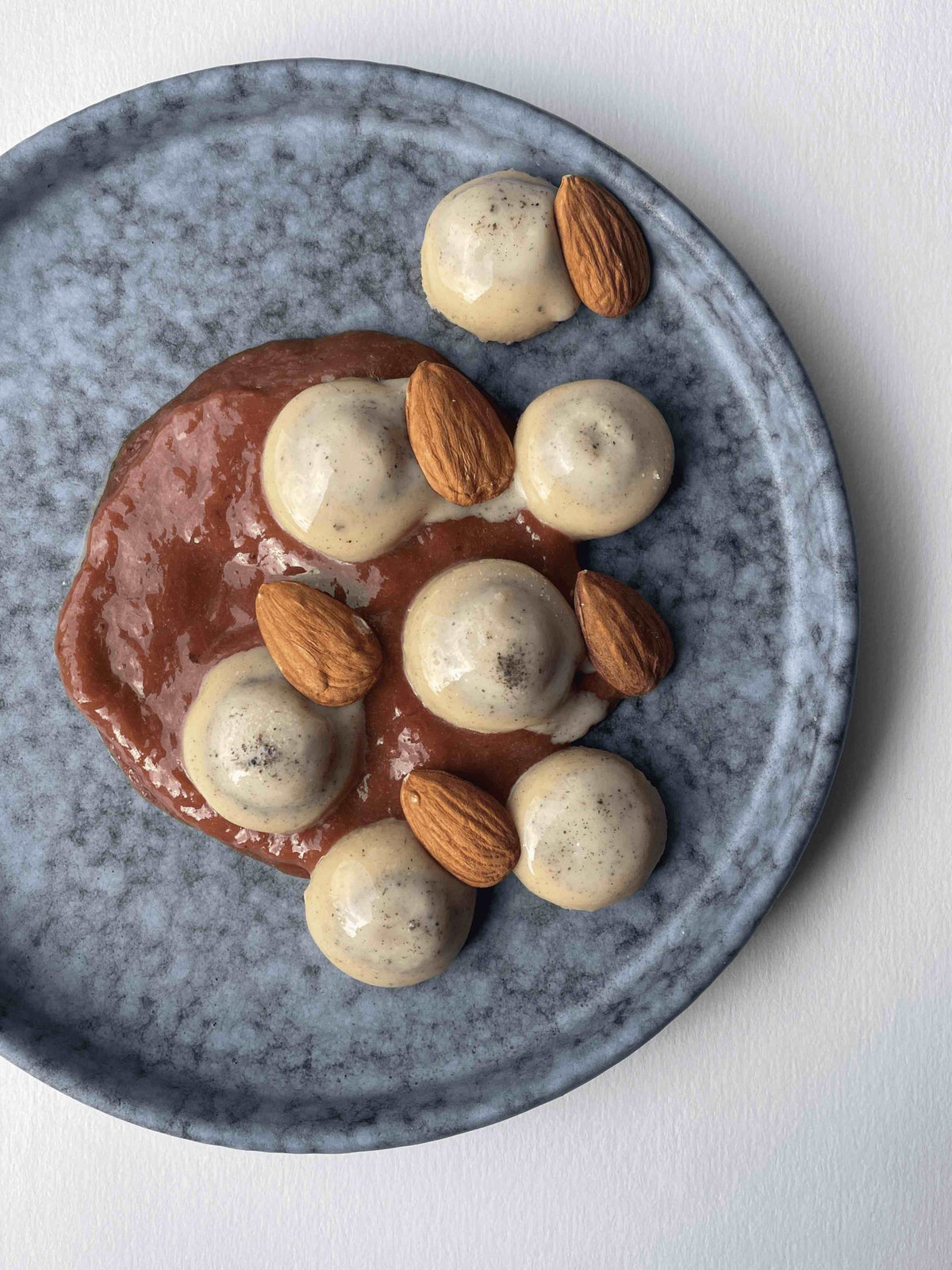 Quenelles of white chocolate and vanilla butter ganache on rhubarb compote with roasted almonds
