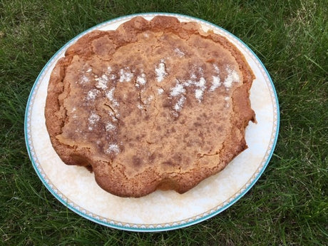 Golden French butter cake baked in a round tin, dusted with vanilla sugar