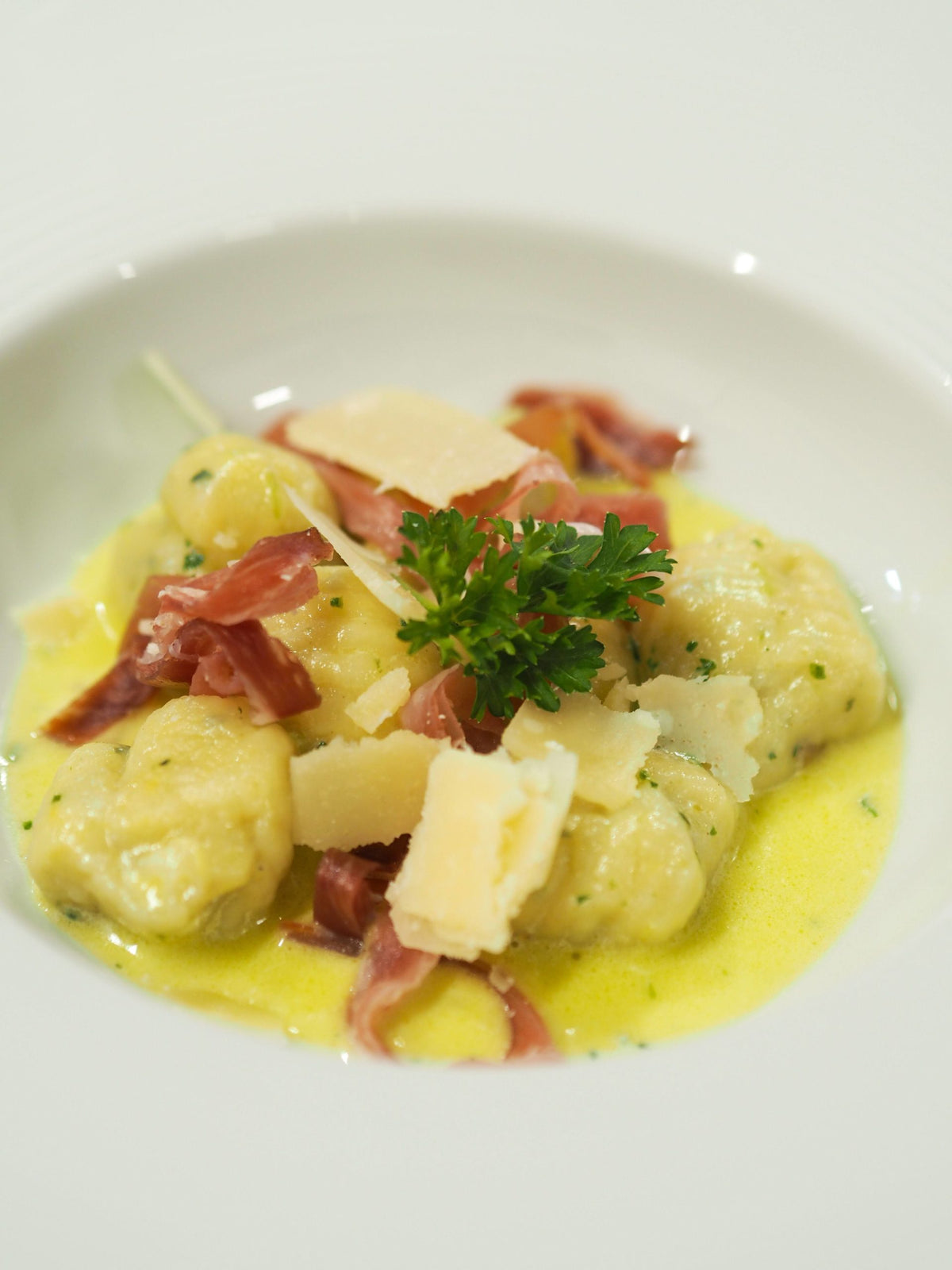 Potato gnocchi in wild garlic butter cream sauce topped with shredded smoked prosciutto and Grana Padano shavings