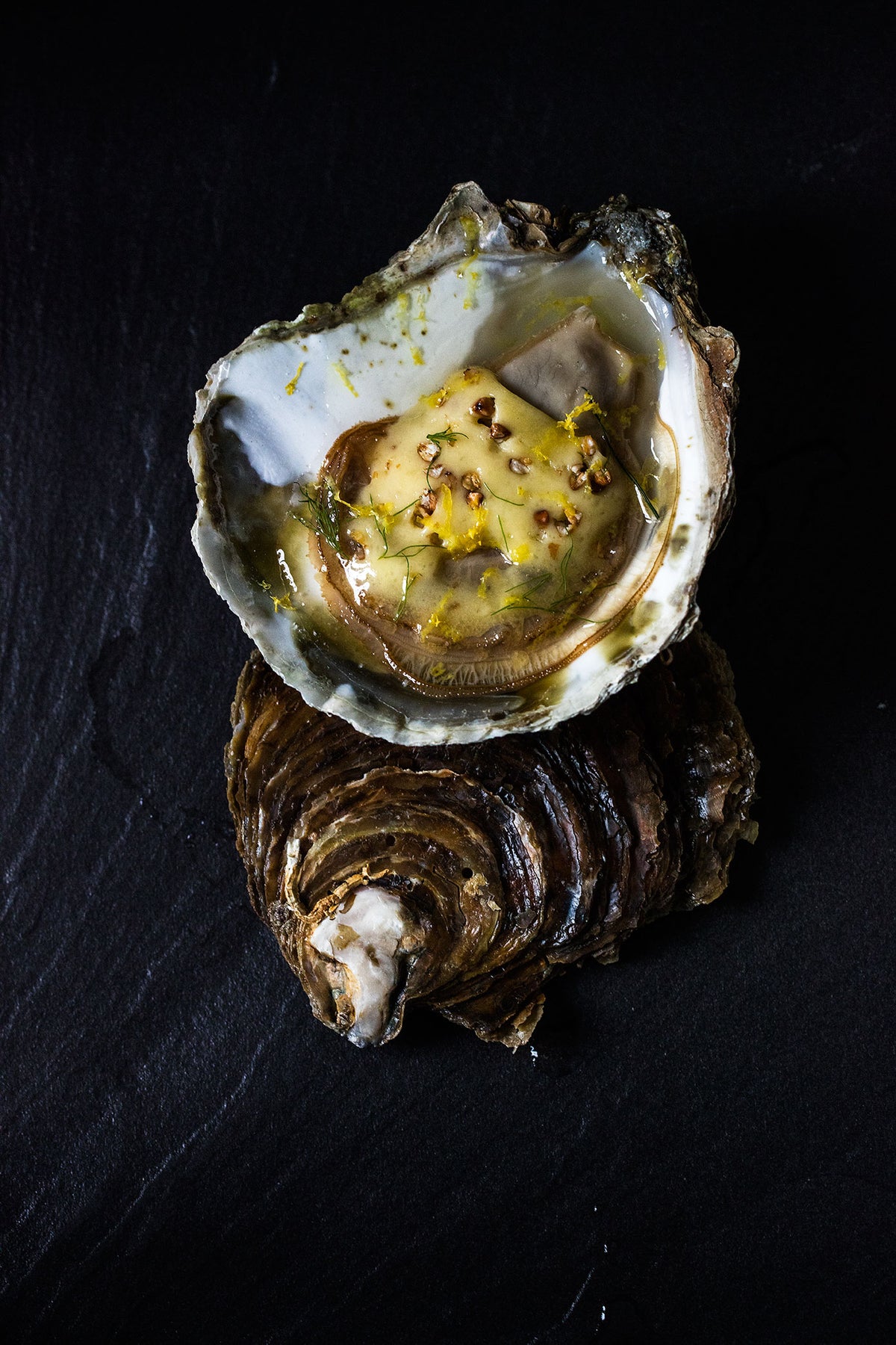 Warm flat oysters topped with shavings of Bordier buckwheat butter, lime zest and dill