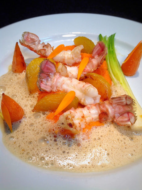 Langoustine tails on carrot purée with glazed baby vegetables and bisque foam
